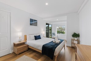 A bedroom with a bed, bedside tables, a nightstand, a window, and a view of greenery outside. - Apartment M204 - coastal and comfortable! (Scarborough)