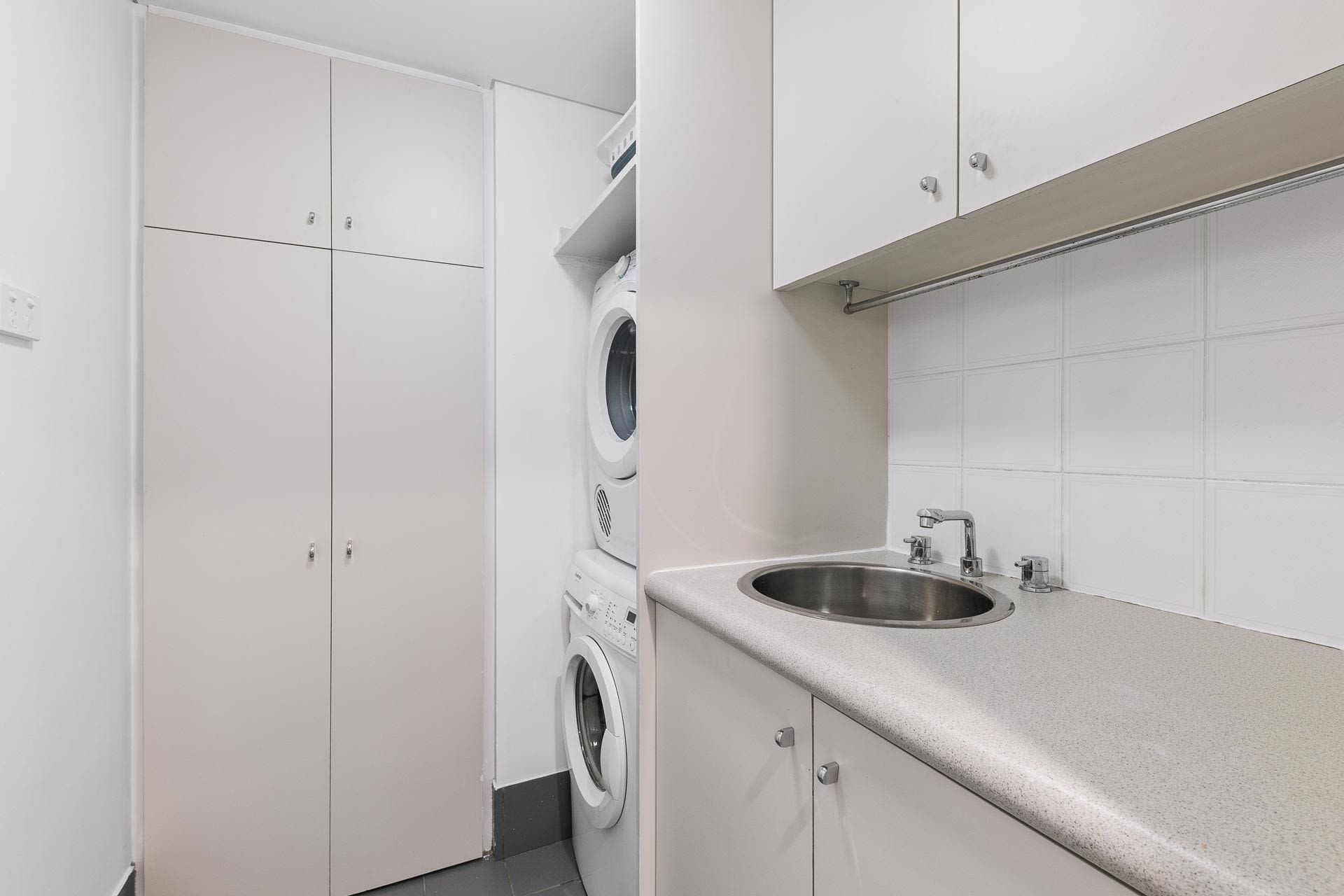 A laundry room with a washing machine, dryer, and a sink with a countertop.