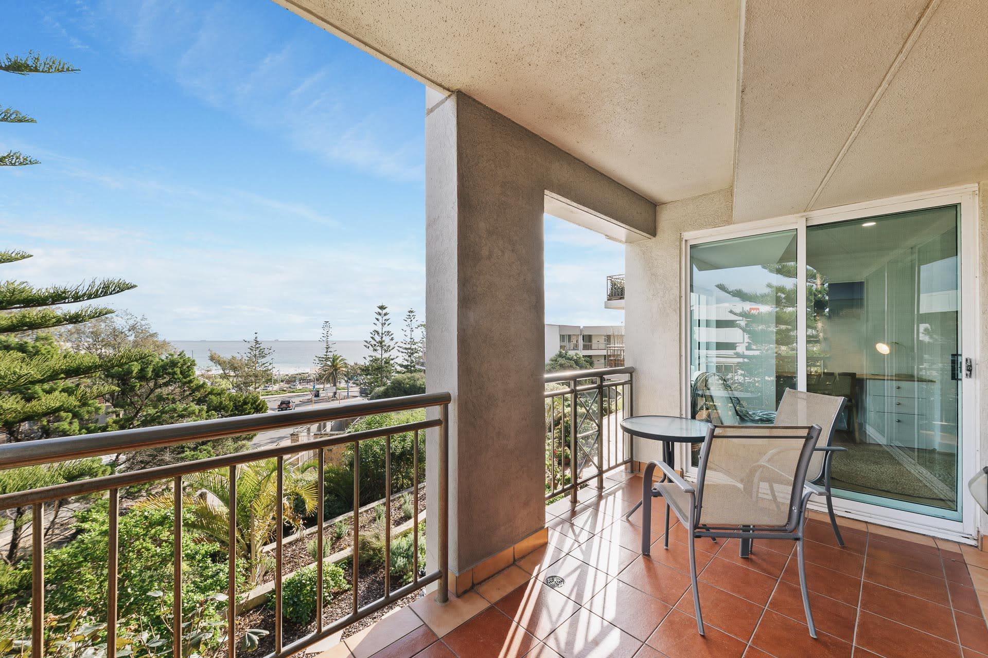 A balcony with a glass door, a chair, and a table.