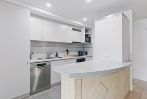 A modern kitchen with white cabinets, stainless steel appliances, and a granite countertop. - Apartment M204 - coastal and comfortable! (Scarborough)