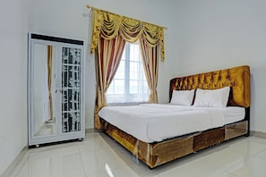 A bedroom with a bed, a wardrobe, and a window with curtains.