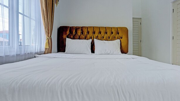 A large bed with white linens and a tufted headboard.