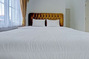 A large bed with white linens and a tufted headboard. - OYO 92708 Hotel Mufasa Syariah (Pangkalpinang)