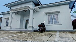 A white building with a porch and a motorcycle parked in front.