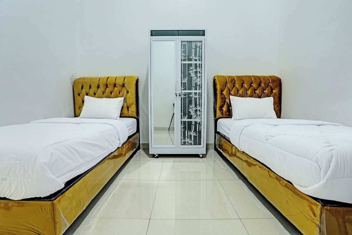 A room with two beds, each with a tufted headboard and white bedding.