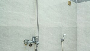 A shower with a handheld showerhead and a wall-mounted faucet.