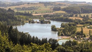Una vista sul lago con un piccolo villaggio, circondato da colline e fitte foreste.