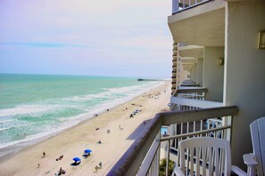 A beach view from a balcony with a pier in the distance. - Garden City Beach Oceanfront Condo 807 | Rising Tides Properties Rental (Murrells)