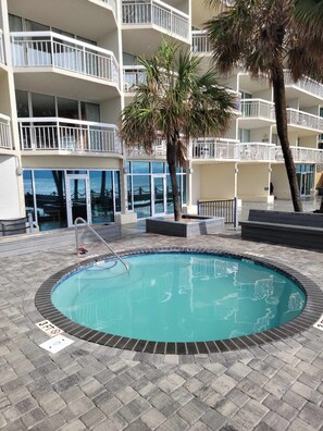 A pool area with a clear view of the ocean, surrounded by a multi-story building with balconies.