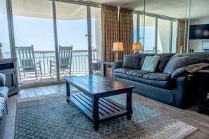 Relax on the balcony with a view of the sea from the comfort of a spacious living room featuring a sofa, coffee table, and flat-screen TV.