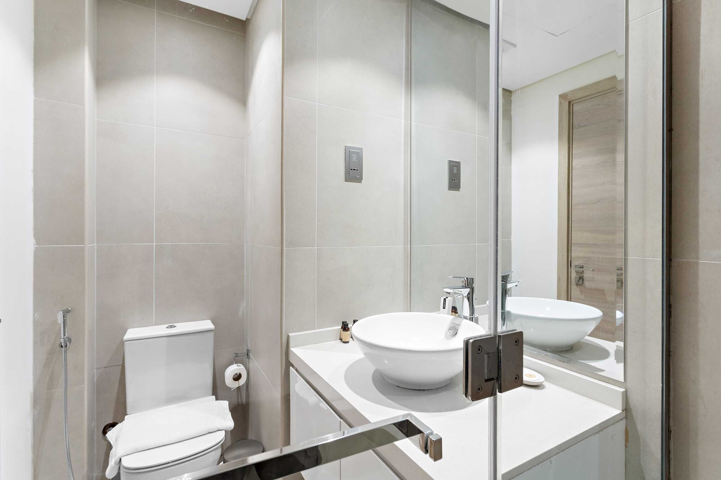 Une salle de bain moderne équipée de toilettes, d’un bidet et d’un grand miroir au-dessus du lavabo.