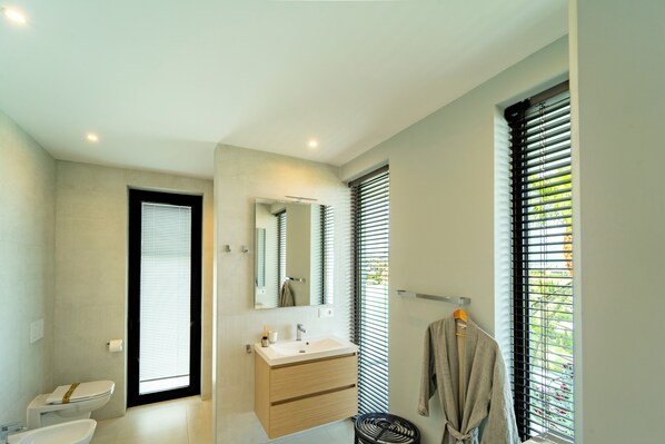 Ein modernes Badezimmer mit Toilette, Waschbecken und Spiegel.