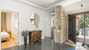 Ein modernes Interieur mit einer Wand aus Stein, einem runden Spiegel und einem Holzkabinett.