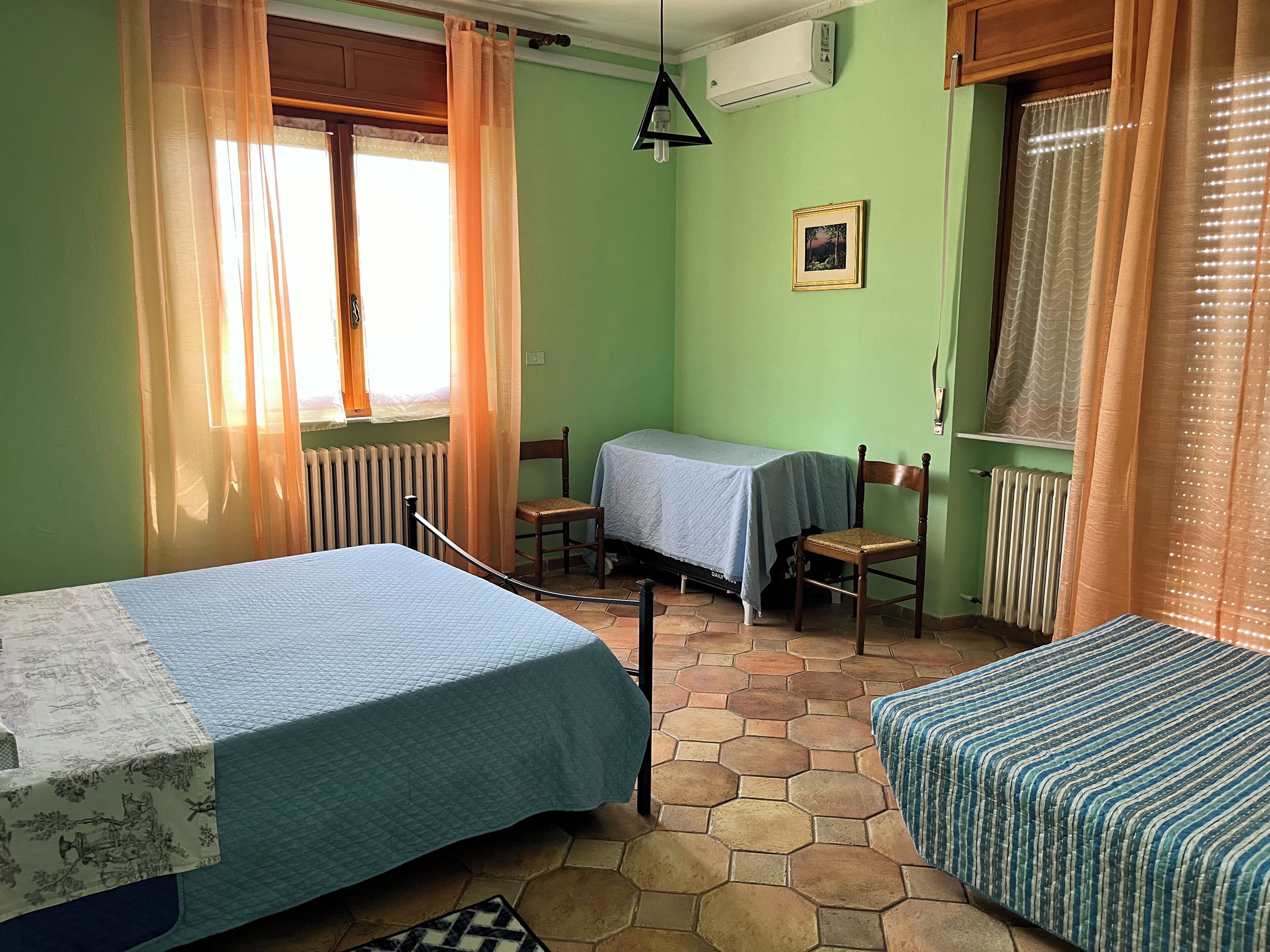 Ein Zimmer mit zwei Betten, einem Tisch, Stühlen und einer Heizung.