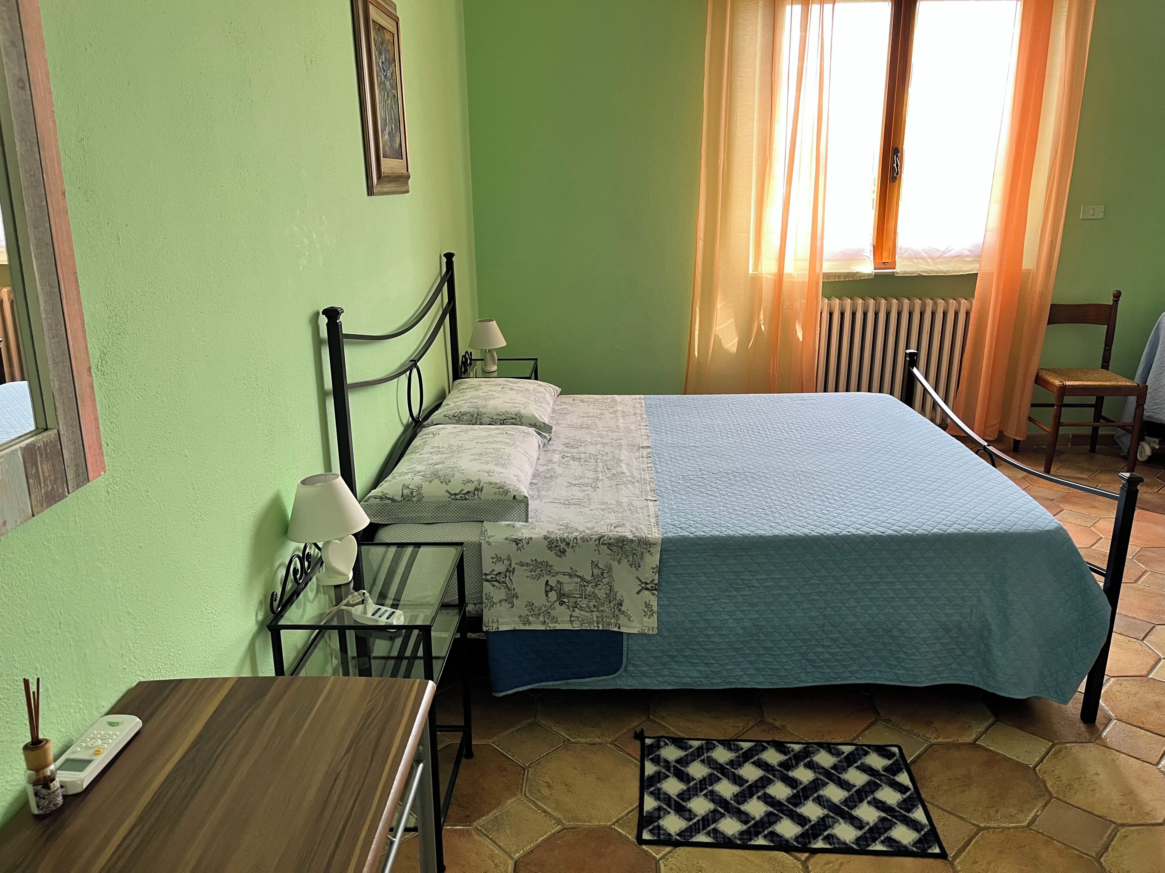 A room with a bed, a table, a chair, a lamp, and a window with curtains.
