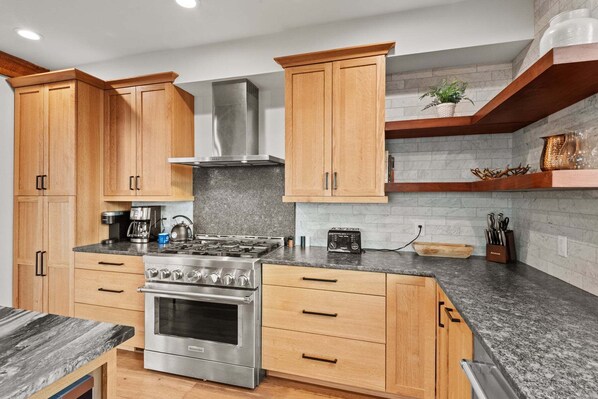 A modern kitchen with wooden cabinets, a stainless steel stove, and a built-in oven.