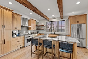 A modern kitchen with wooden cabinets, a stainless steel stove, and a large island with bar stools.
