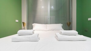 Ein Hotelzimmer mit Bett, weißen Handtüchern und einem Fenster mit Jalousien.