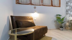 A brown leather sofa with a glass table, a wall-mounted light, a potted plant, and a floral wallpaper pattern. - Italianway - Orti 5 (Milan)