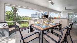 An outdoor dining area with a table set for two, surrounded by wicker chairs.