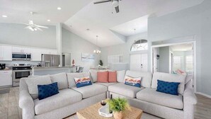 A modern living room with a sectional sofa, a coffee table, and a kitchen in the background.