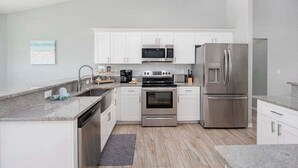 A modern kitchen with white cabinets, stainless steel appliances, and a granite countertop.