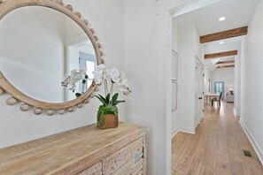 A hallway with a wooden dresser, a large mirror with a wooden frame, and a potted plant with white flowers. - Dixieland Delight at River Rocks Plantation (Guntersville)