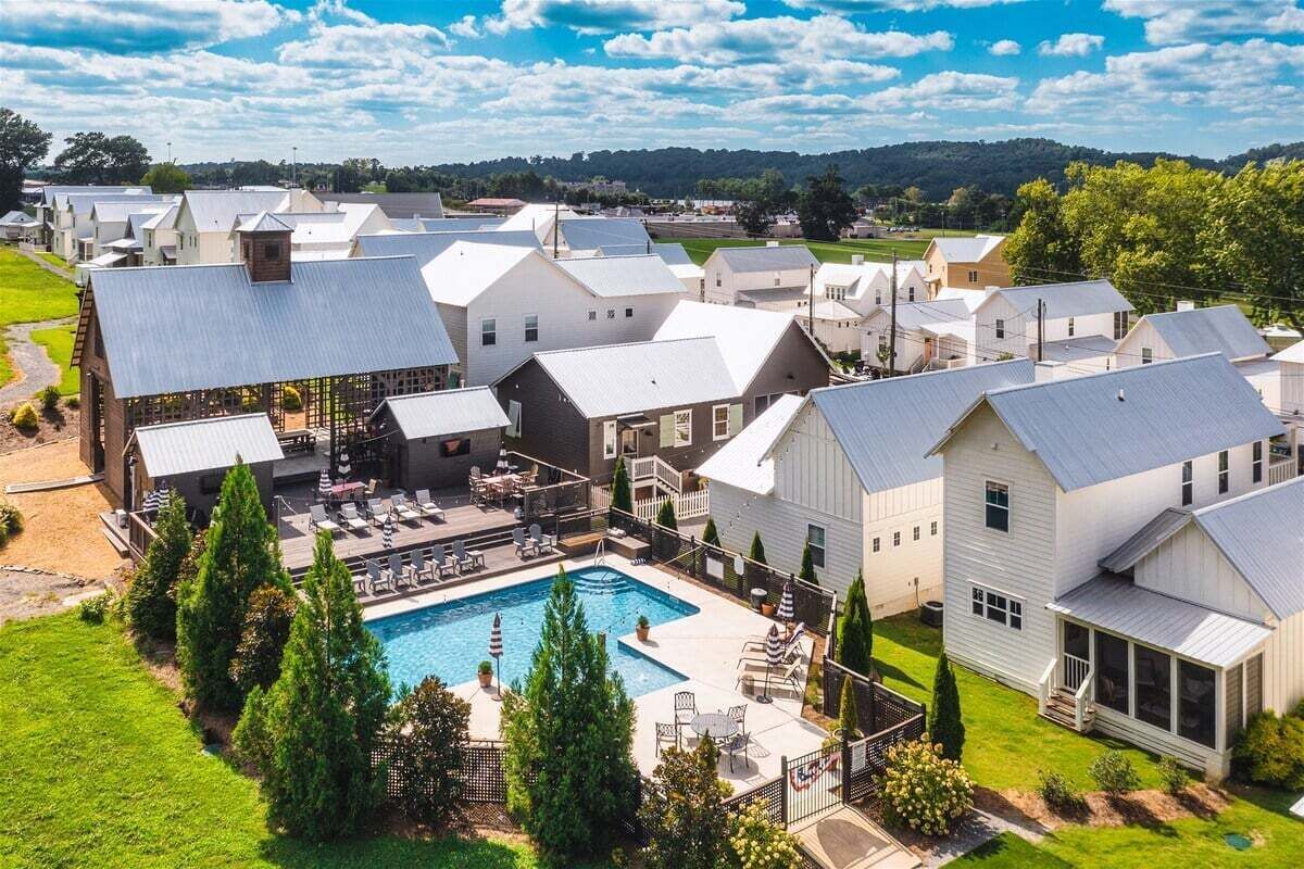 A residential area with multiple houses, a swimming pool, and a fenced yard.