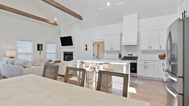 A spacious living area with a dining table, white furniture, and a kitchen with white cabinets and a large refrigerator. - Dixieland Delight at River Rocks Plantation (Guntersville)
