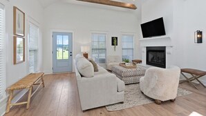 A spacious living room with a fireplace, a television mounted on the wall, and a bench. - Dixieland Delight at River Rocks Plantation (Guntersville)