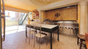 Une cuisine avec coin repas, comprenant un grand îlot central, des appareils en acier inoxydable et un élément décoratif mural.