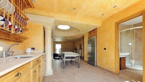 Une cuisine spacieuse dotée d’un îlot central, d’un réfrigérateur encastré et d’un coin repas avec une table et des chaises.