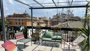 Une terrasse sur le toit avec un canapé vert, des chaises colorées et des plantes en pot.
