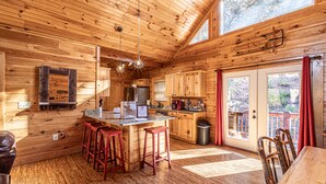 A wooden cabin interior with a kitchen, bar area, and dining space.