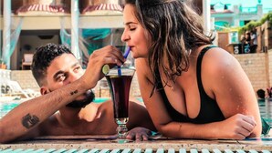Een koppel ontspant zich bij het zwembad met een drankje.