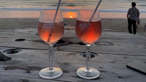 Two glasses of Aperol Spritz on a wooden table with a sunset view. - Maison au Calme ,proche du Centre Ville, des Plages, des Tennis, Surf, Beach (Soulac-sur-Mer)