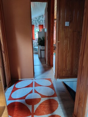 A hallway with a patterned rug, wooden walls, and a door leading to another room. - Maison au Calme ,proche du Centre Ville, des Plages, des Tennis, Surf, Beach (Soulac-sur-Mer)