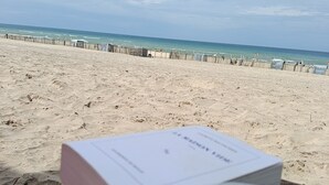 Strandudsigt med en bog og en kop kaffe på et bord.