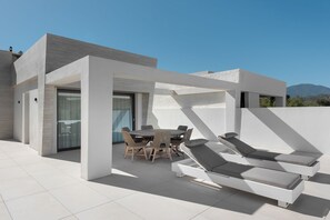 A modern outdoor patio with a dining area and lounge chairs. - Exceptional 3 bedroom duplex penthouse in Epic Marbella (Marbella)
