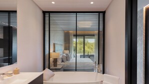 A modern bathroom with a bathtub, a vanity with a mirror, and a window with horizontal blinds. - Exceptional 3 bedroom duplex penthouse in Epic Marbella (Marbella)