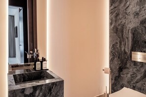 A modern bathroom with a marble sink, a mirror, and a marble wall. - Exceptional 3 bedroom duplex penthouse in Epic Marbella (Marbella)