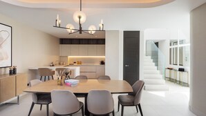 A modern kitchen with integrated appliances, a dining area with a large table and chairs, and a staircase leading to an upper level. - Exceptional 3 bedroom duplex penthouse in Epic Marbella (Marbella)