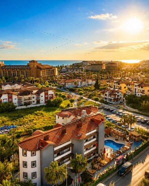 A resort with multiple buildings, a swimming pool, and a view of the sea. - MERYAM SUIT DELUX HOTEL (Manavgat)