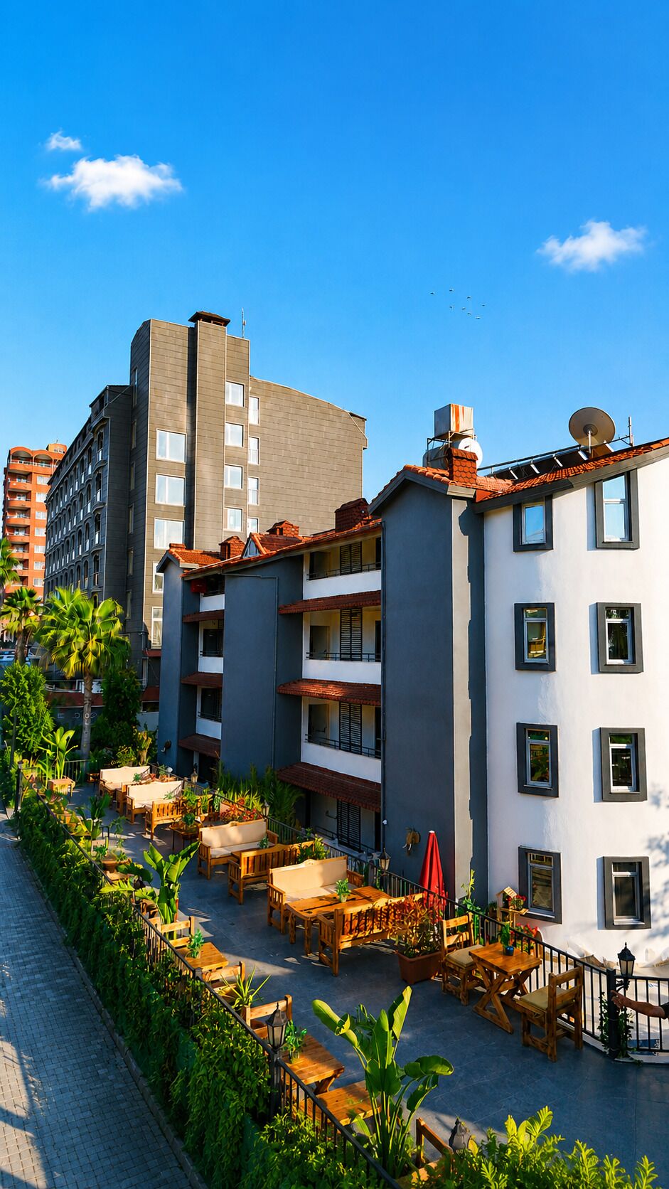 Un edificio de varios pisos con zonas de estar al aire libre, balcones y un cielo azul despejado.