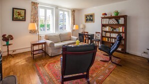 A living room with a sofa, armchair, and a bookshelf. - L'If, ground floor flat in a beautiful house, close to the beach (Varengeville-sur-Mer)