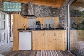 Eine kompakte Küche mit Holzschränken, einem eingebauten Geschirrspüler und einer Steinwand.
