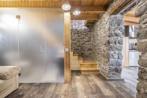 Une pièce avec un mur en pierre, un escalier en bois et une porte coulissante.