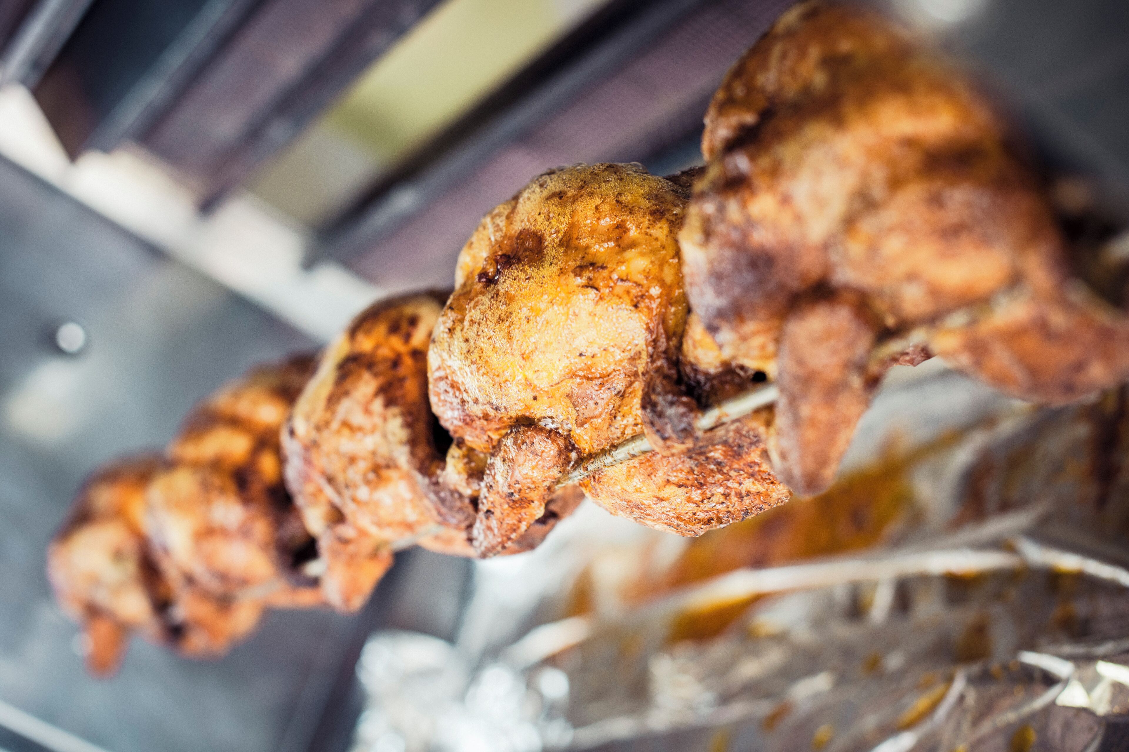 Primer plano de brochetas de pollo asado con una costra dorada, probablemente sazonadas con hierbas y especias.