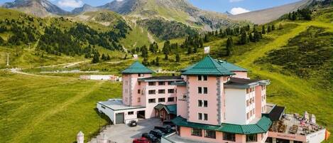 A hotel with a central tower, multiple wings, and a mountain backdrop.