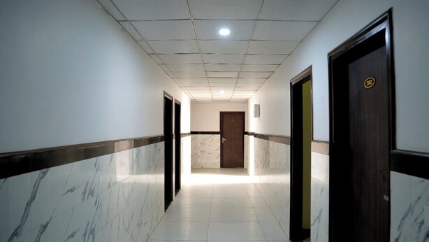 Un pasillo con paredes y puertas de mármol que conduce a una habitación con puerta de madera.
